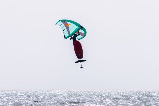 Abdo jumping with his wing and foil board above the lagoon